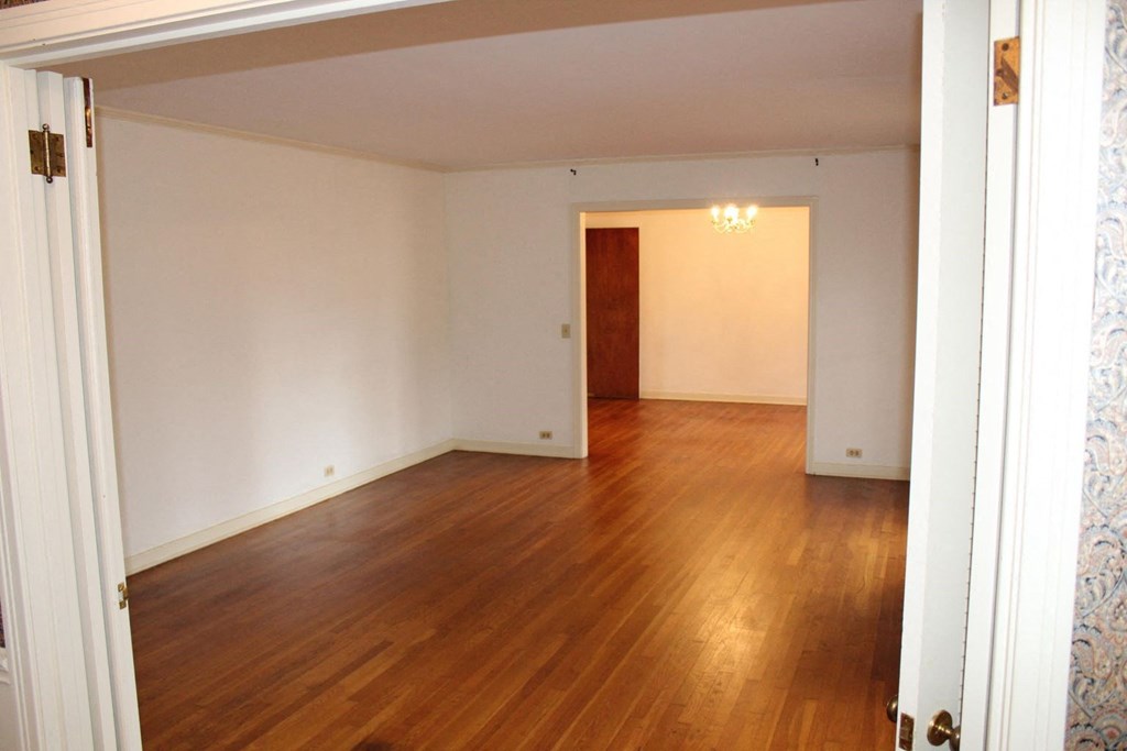 an empty living room with wood floors and white walls