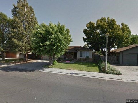 A street view of a residential area with houses and trees.