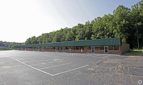 a parking lot with a building and trees in the background