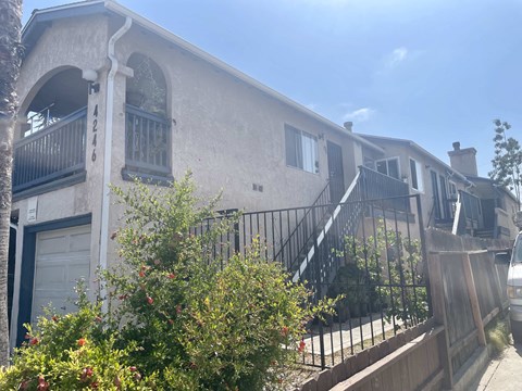 the front of a house with stairs and a fence