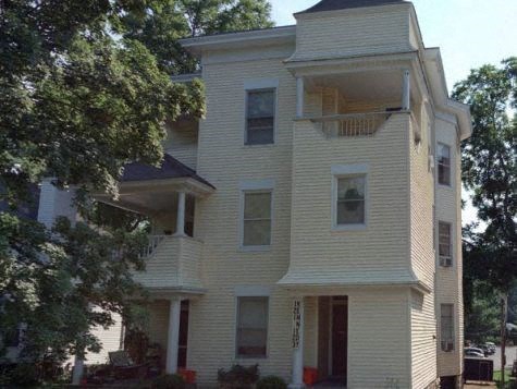 A white two-story apartment building with balconies and a small porch.