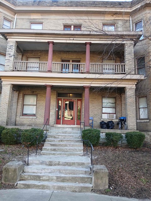 A brown building with a red door and steps leading up to it.