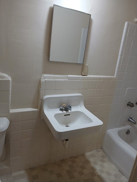 A white sink in a white tiled bathroom.