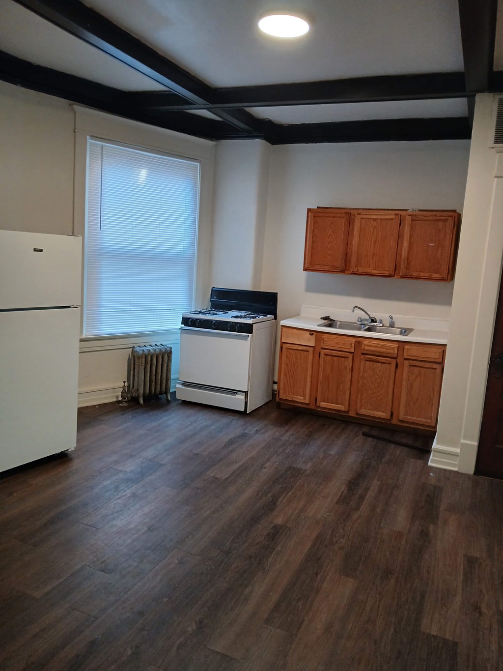 A kitchen with a white refrigerator, wooden cabinets, and a white stove top oven.