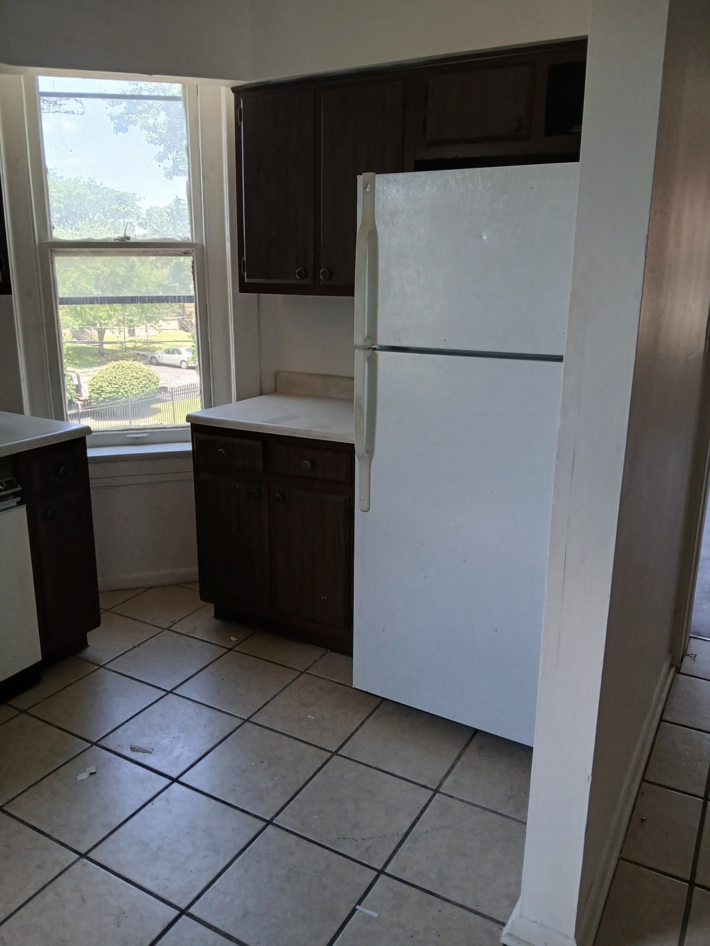 an empty kitchen with a refrigerator and a window