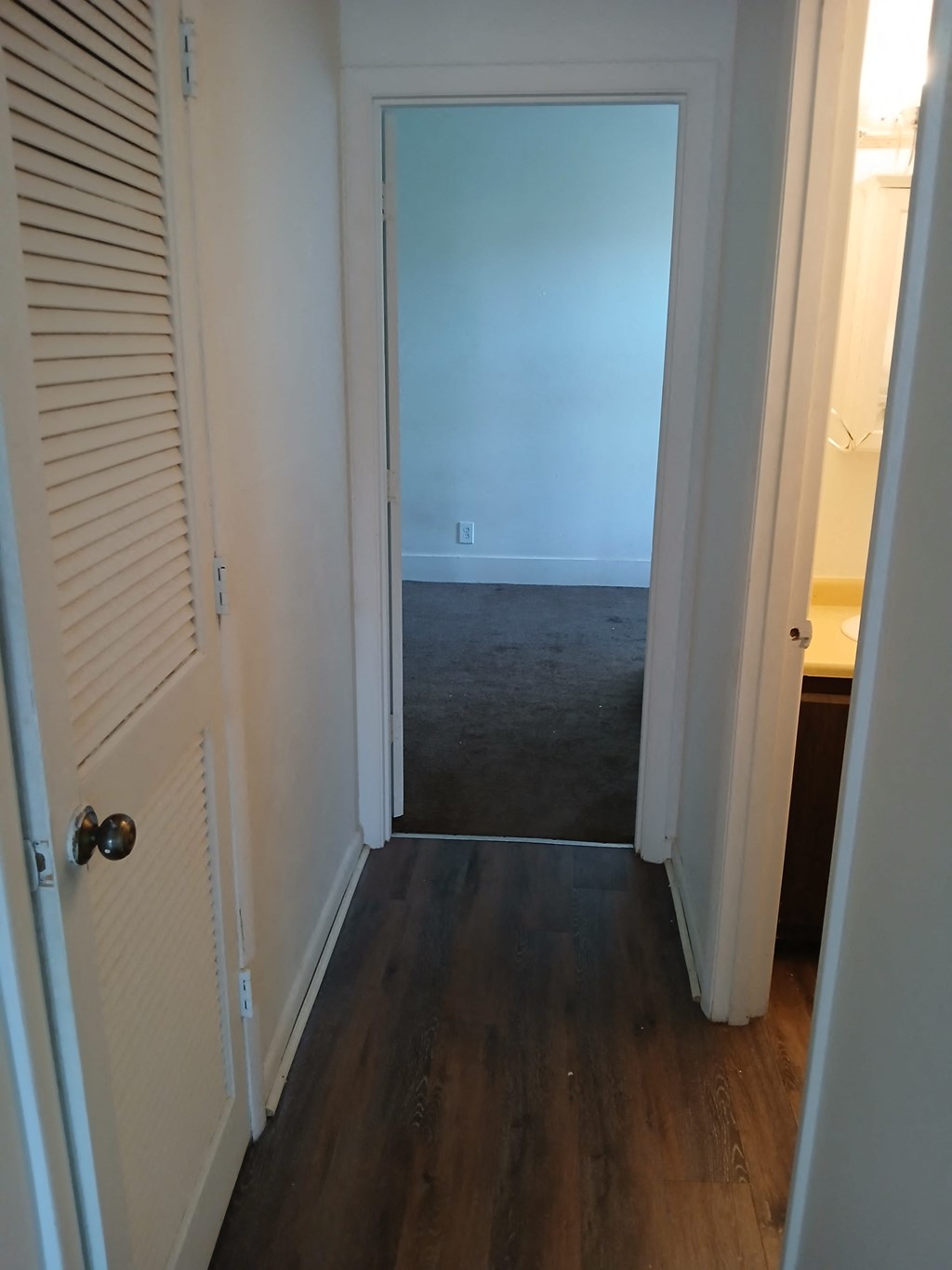 a hallway with a door to a room with a carpeted floor