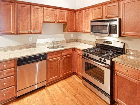 A kitchen with wooden cabinets and a stainless steel dishwasher.