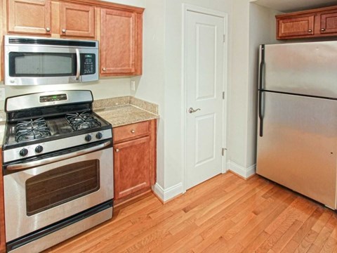 A kitchen with wooden cabinets and a stainless steel refrigerator.
