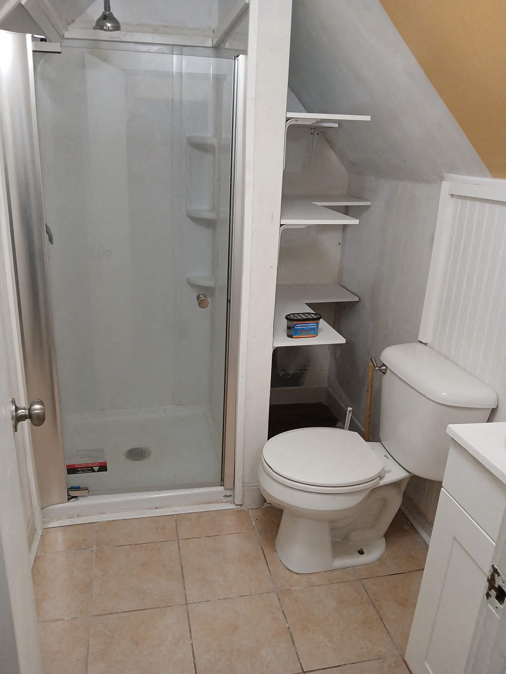 A white toilet in a small bathroom with a walk-in shower.