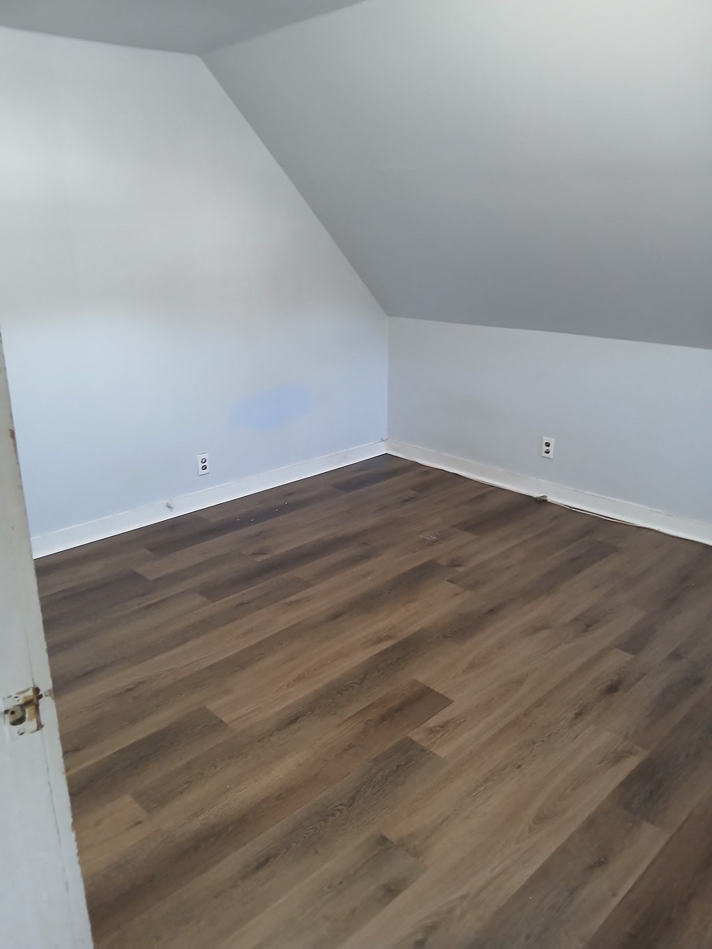 A room with wooden flooring and white walls.