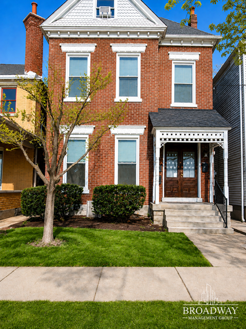 A red brick house with a tree in front of it.