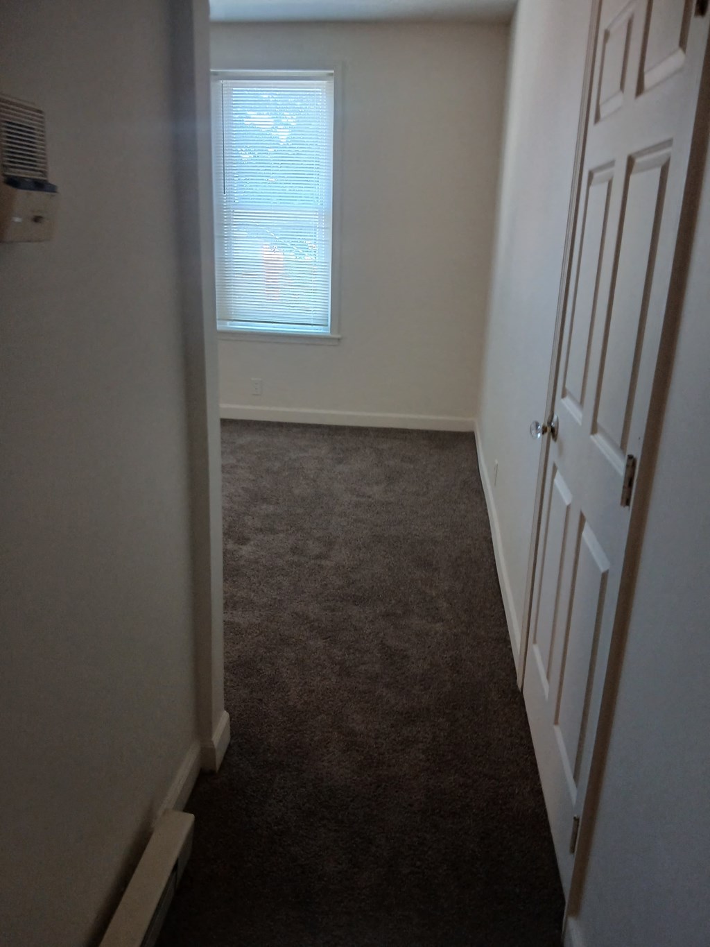 a room with a carpeted floor and a window and a door