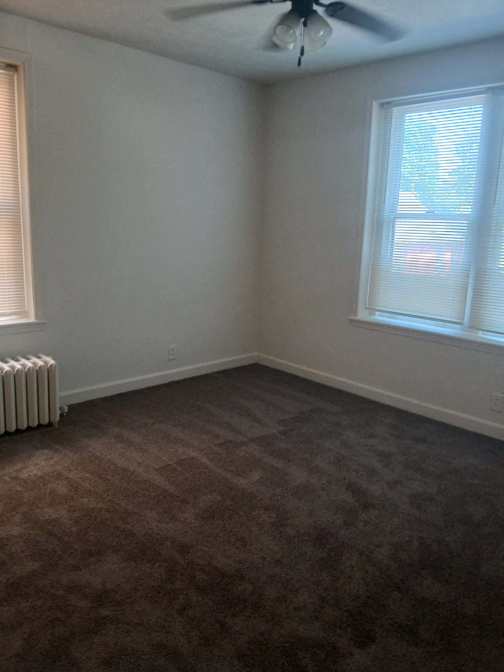 an empty room with a heater and two windows
