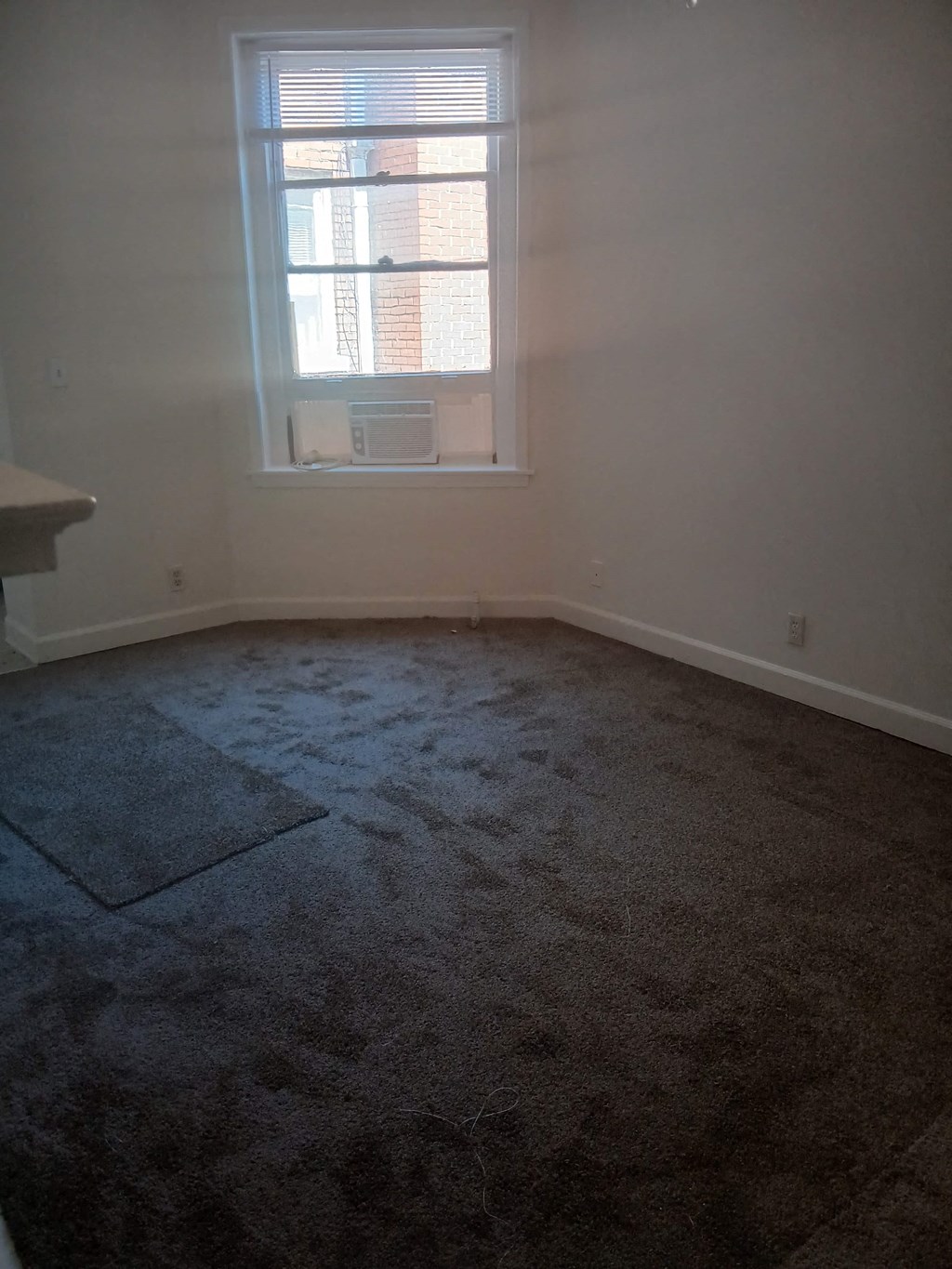 an empty room with a window and a carpeted floor