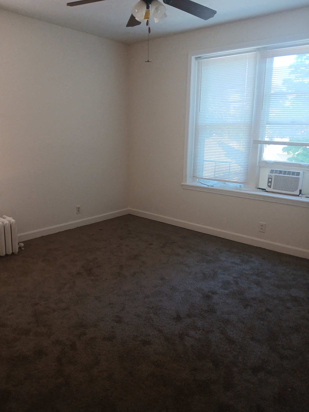 an empty room with a window and a ceiling fan