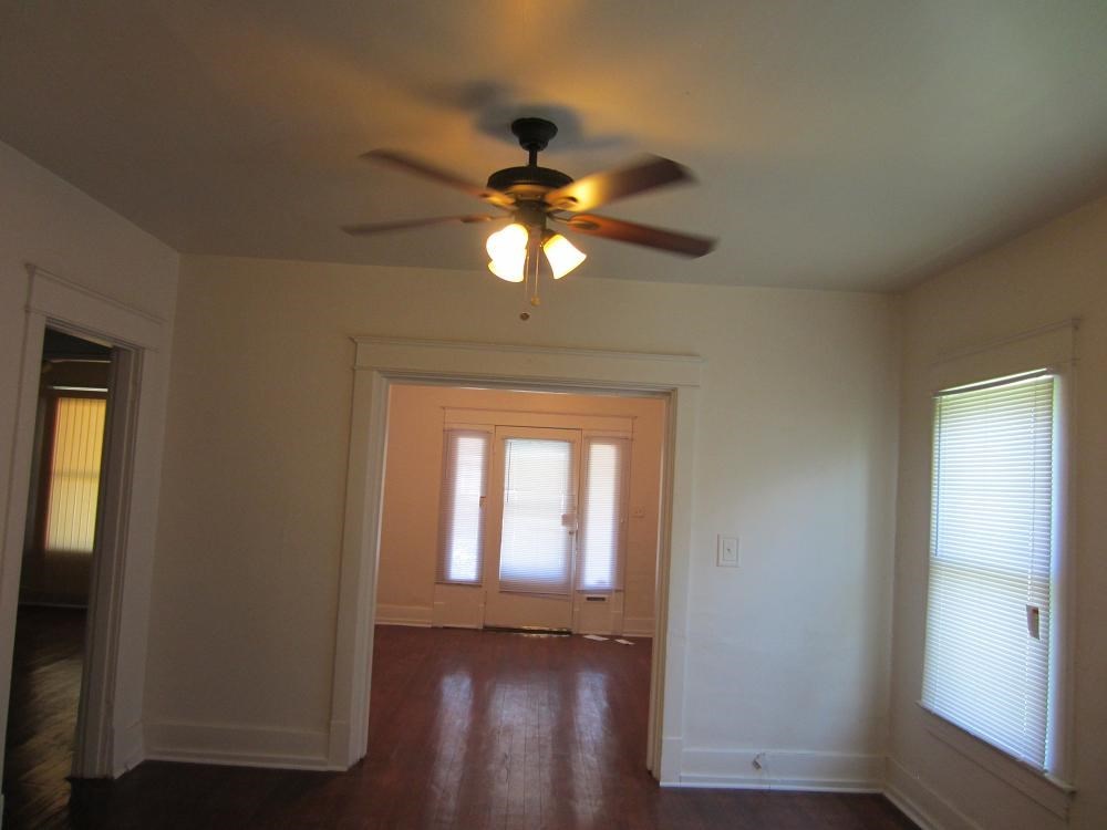 an empty living room with a ceiling fan and a door