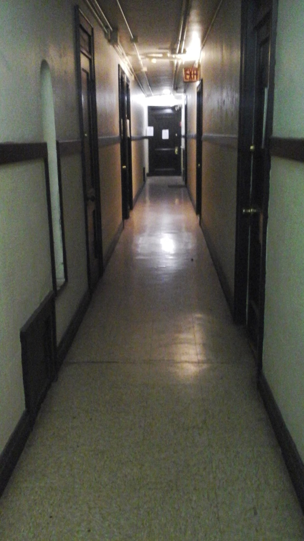 a hallway in a building with doors and a light on the floor