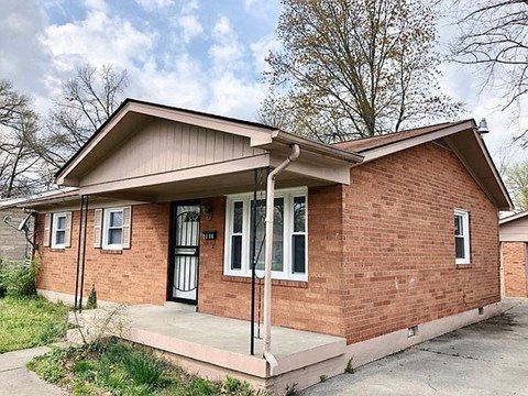 A small brick house with a black door and a porch.