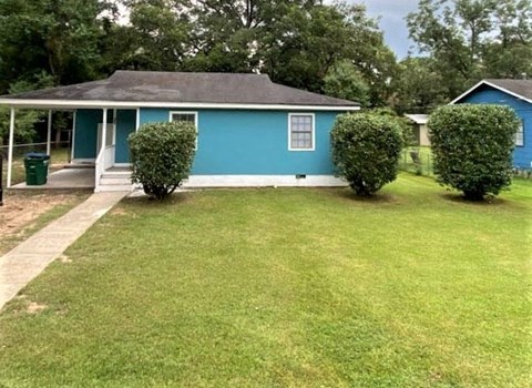 A blue house with a green trash can in front of it.
