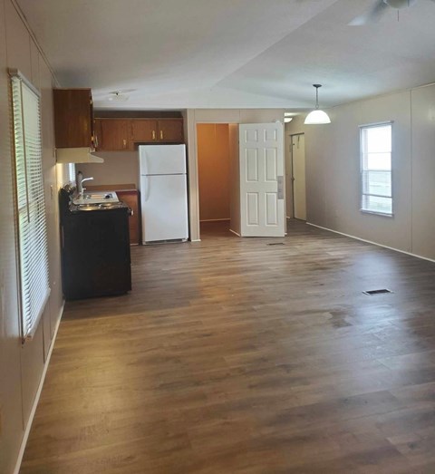 A kitchen with a black fridge and wooden floors.
