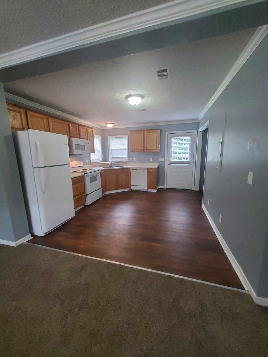 an empty kitchen with wooden floors and a white refrigerator
