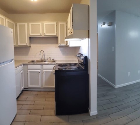 A kitchen with a black dishwasher and white appliances.