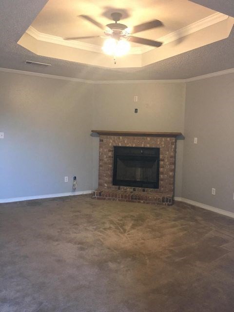 A living room with a fireplace and a ceiling fan.