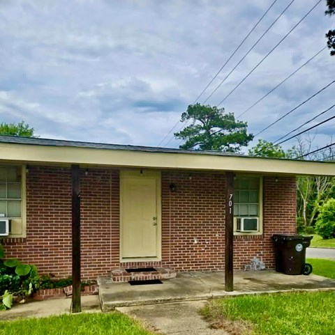 A house with a brown brick wall and a white door.
