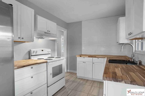 A modern kitchen with white cabinets and a wooden countertop.