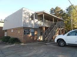 A white car is parked in front of a two-story building.