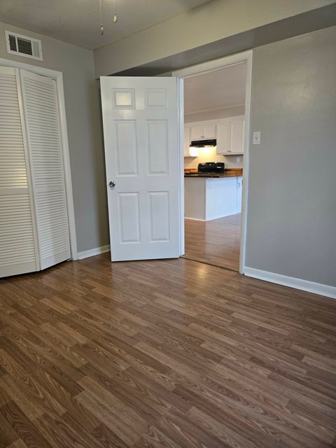 A room with a white door and wooden flooring.