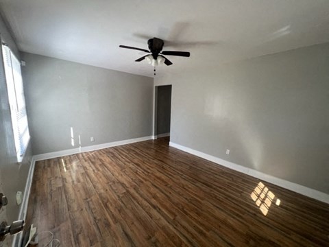 a living room with wood floors and a ceiling fan