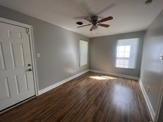 an empty living room with a ceiling fan and wood floors