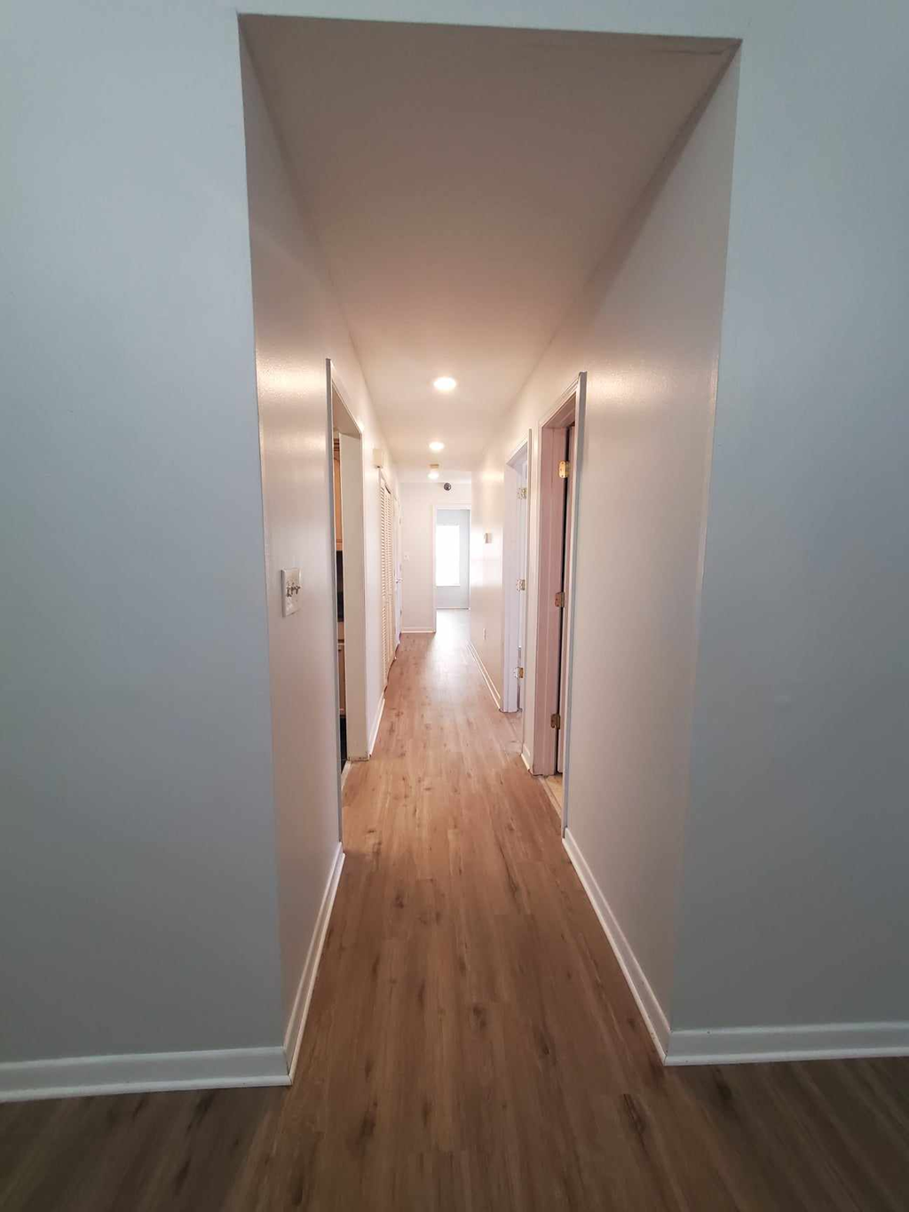 a long hallway with white walls and wooden floors