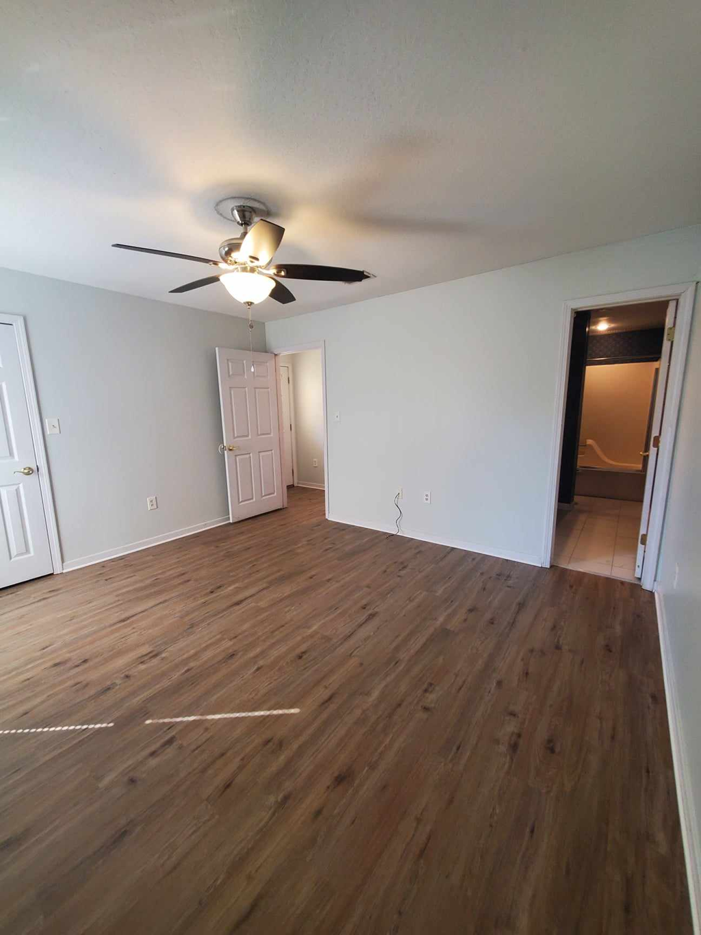 an empty living room with wood flooring and a ceiling fan