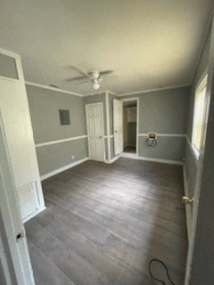 A room with a ceiling fan and light, wooden floors, and a white door.