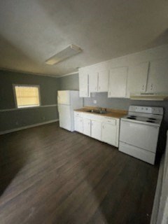 A kitchen with white appliances and wooden floors.