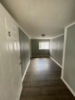 A long hallway with a white door on the left and a window on the right.