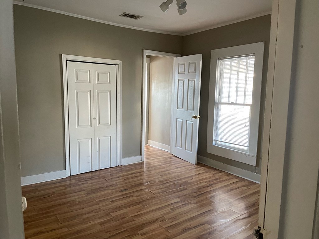 an empty room with wood floors and two doors and a window