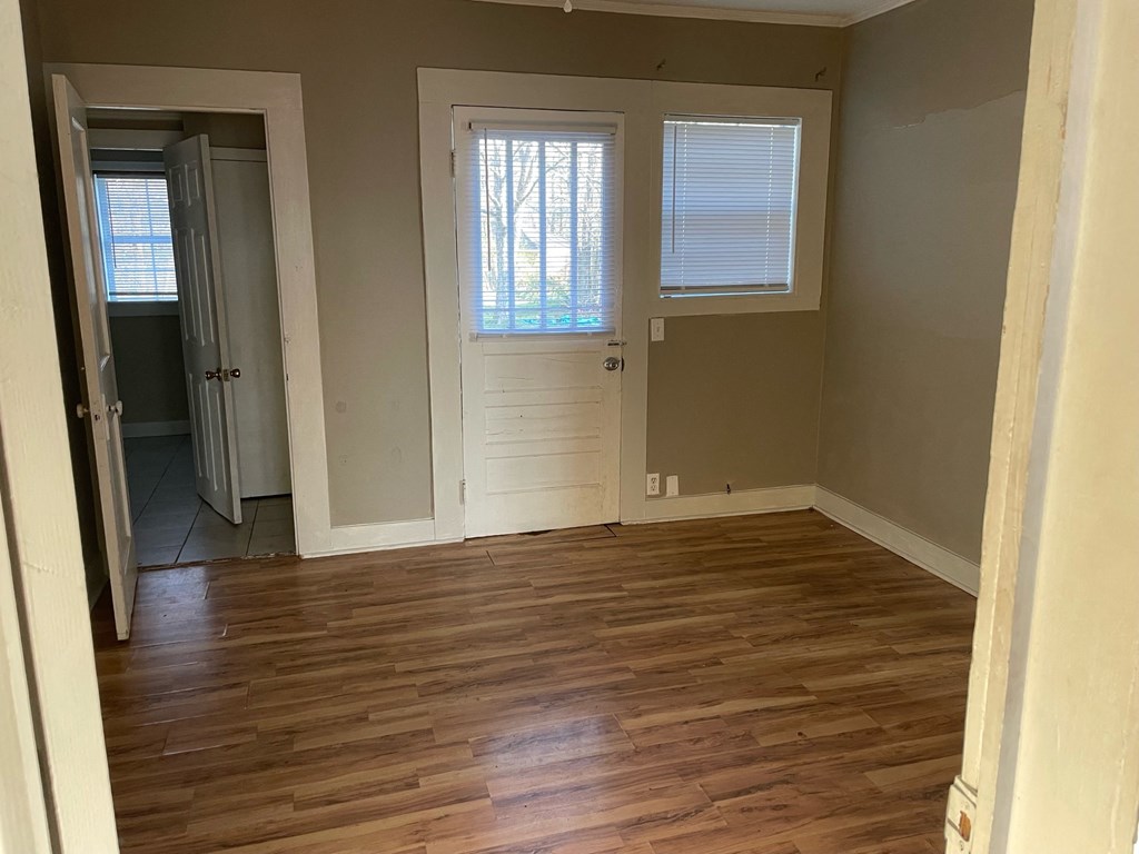 an empty living room with wooden floors and a white door