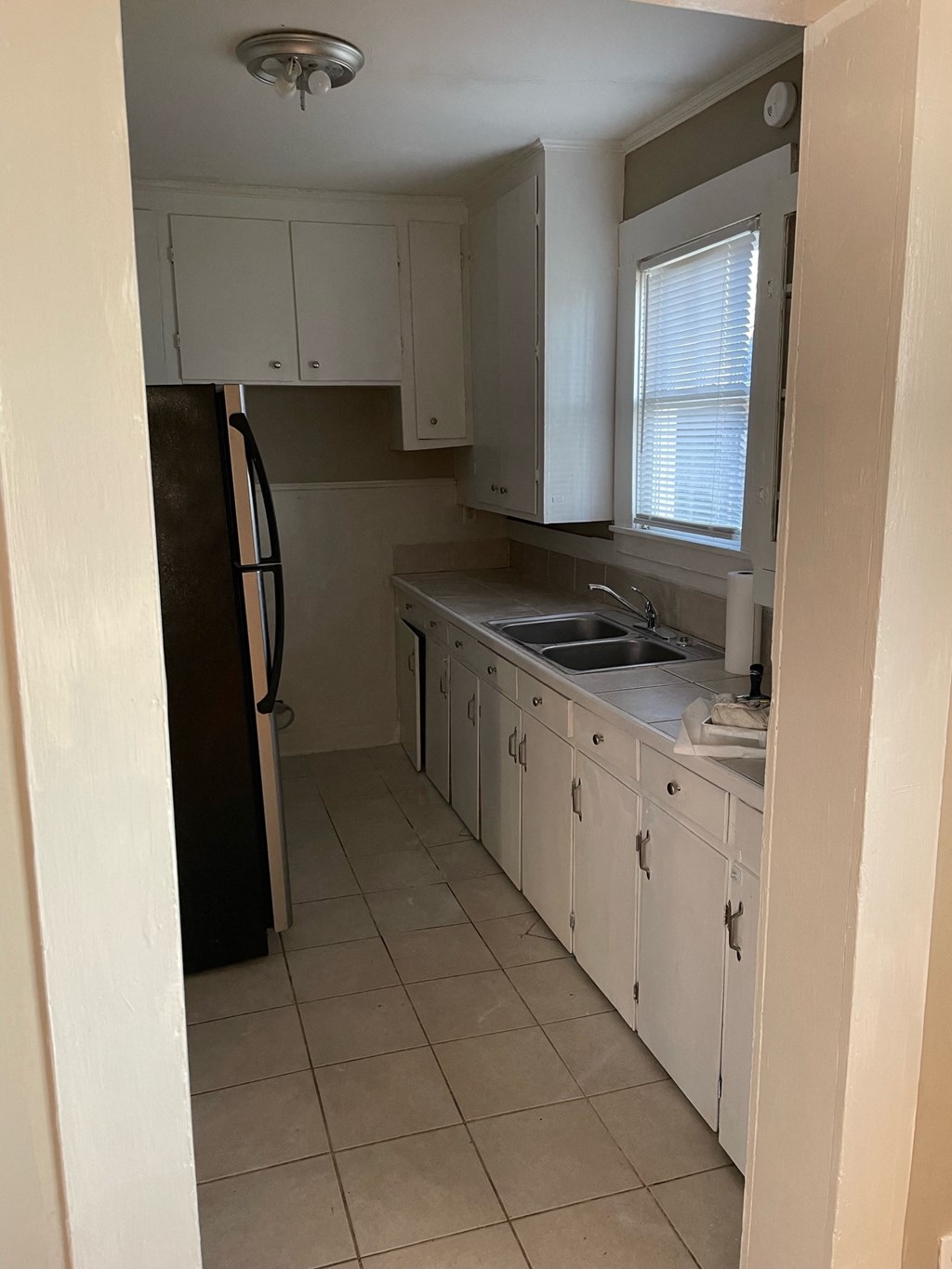 a kitchen with white cabinets and a sink and a refrigerator