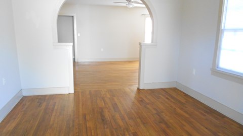 an empty living room with wooden floors and white walls