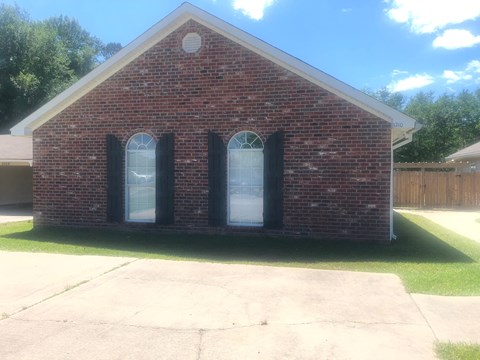 A small red brick house with a white door and two windows.
