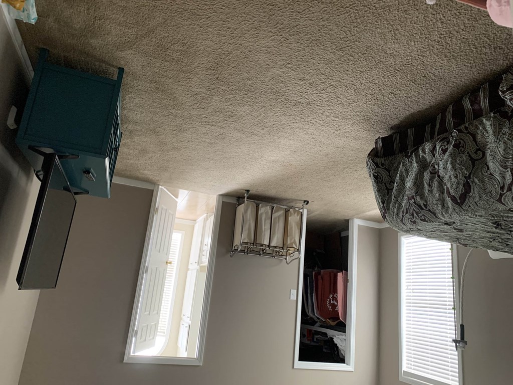 a view of the ceiling of a bedroom with a closet and a window with curtains