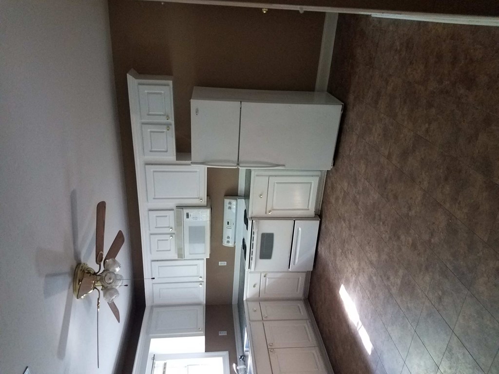 a kitchen with white cabinets and a ceiling fan
