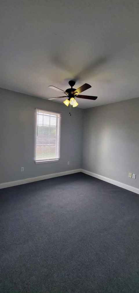 A room with a ceiling fan and a window.
