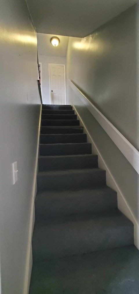 A staircase with a light on the ceiling and a door at the top.