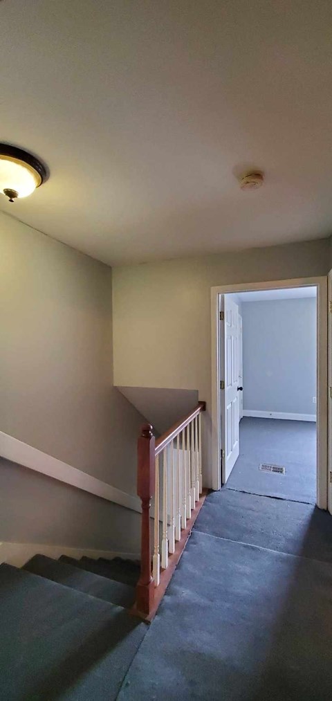 A staircase with a wooden railing and a light on the ceiling.