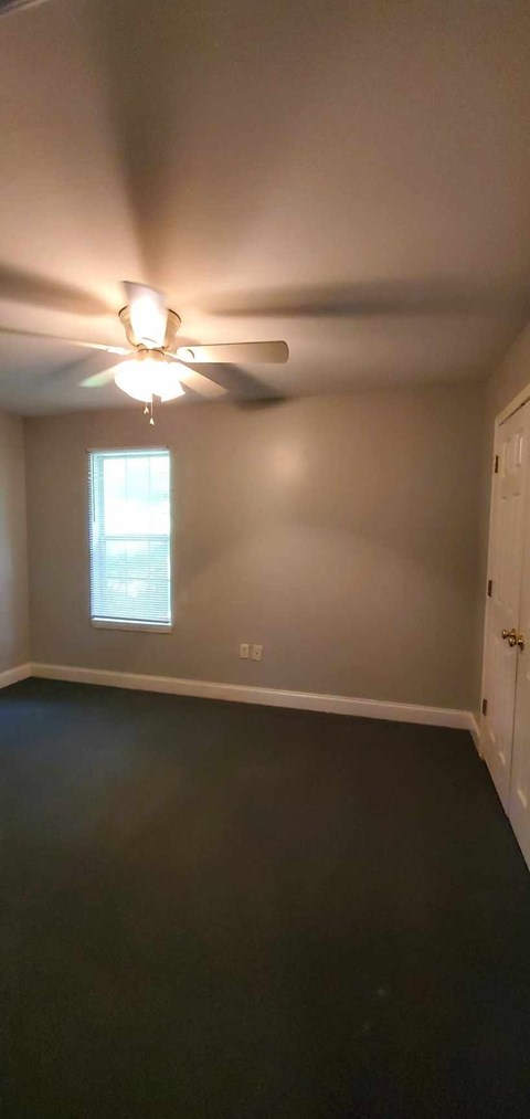 A room with a ceiling fan and a window.