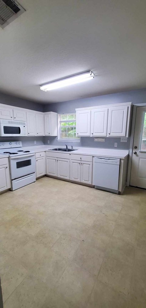 A kitchen with white cabinets and a tiled floor.
